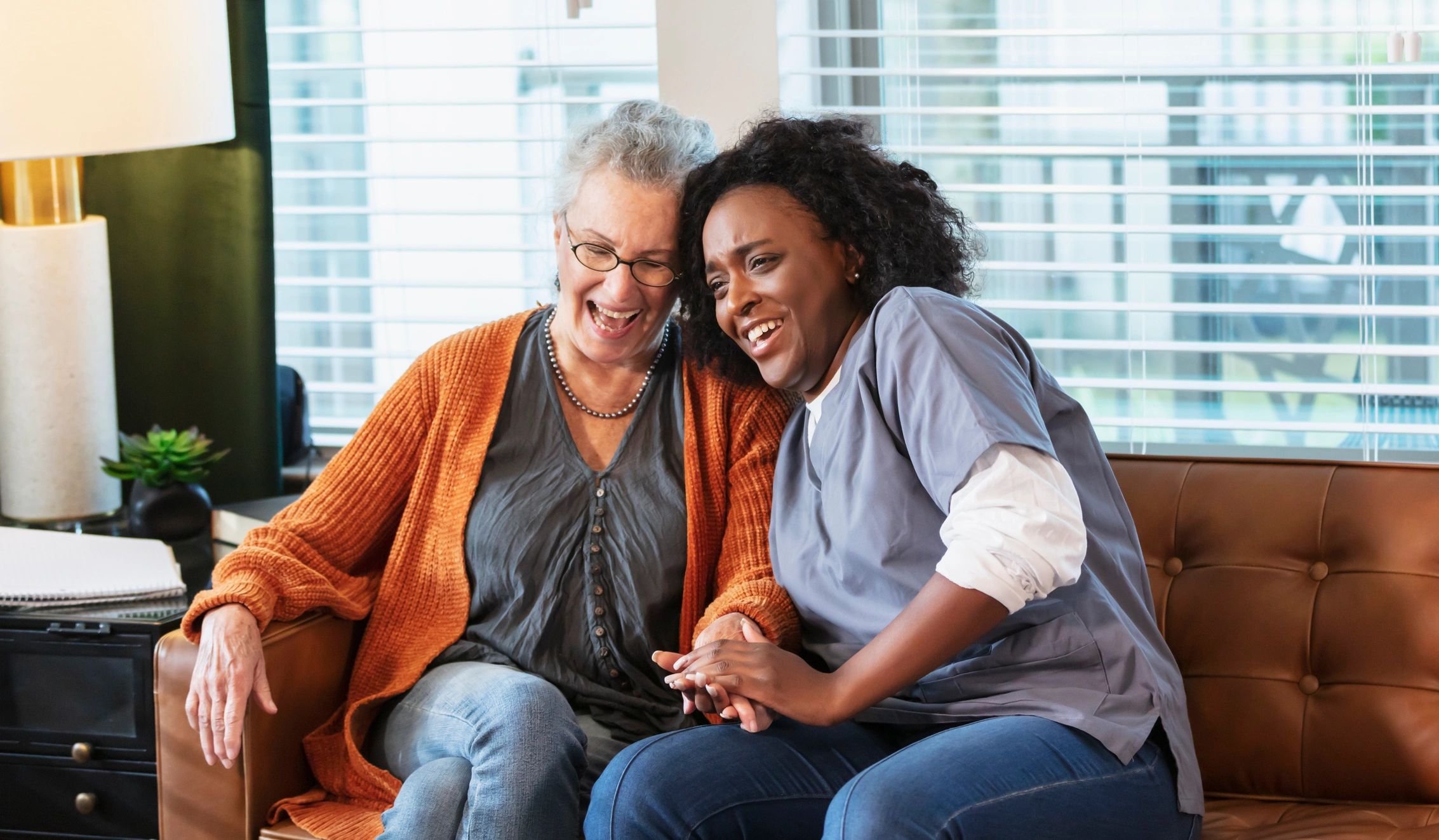 Caregiver holding a senior's hand while they sit together at home in Houston