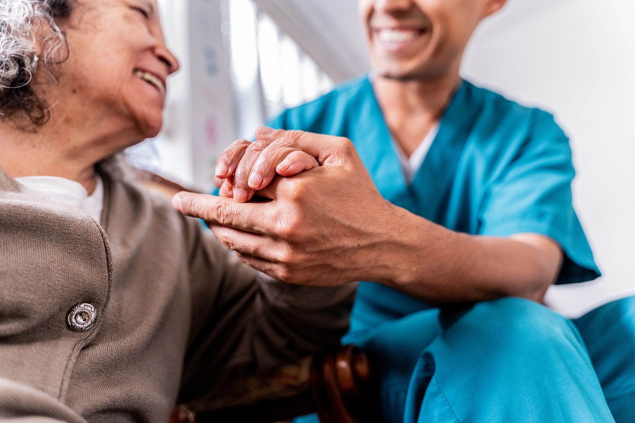 Caregiver holding a senior's hands in a reassuring moment at home in Houston