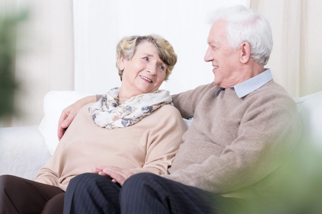 Adult daughter sitting compassionately with her elderly mother with dementia at home