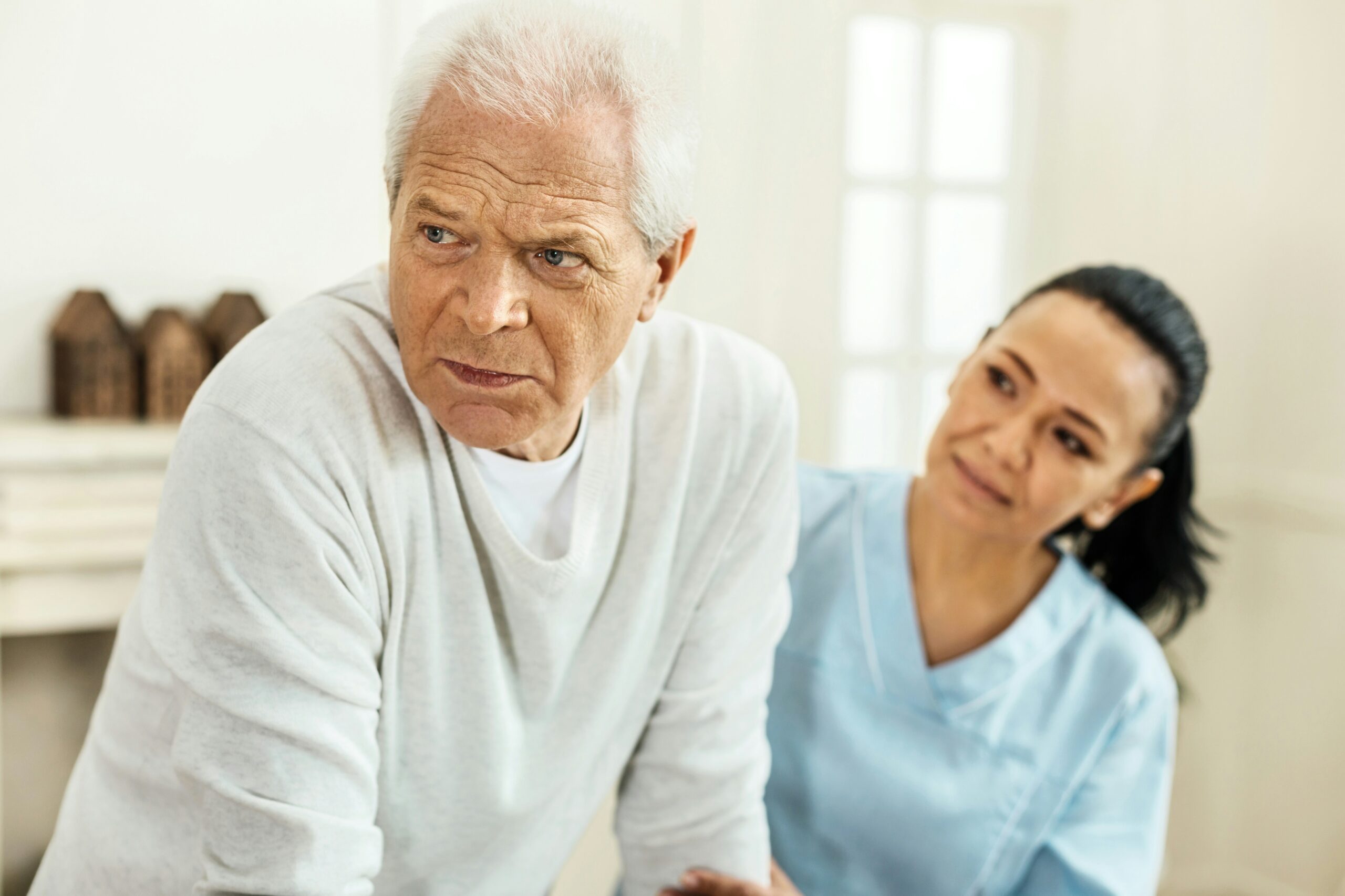 Compassionate caregiver holding the hand of an elderly person with dementia at home